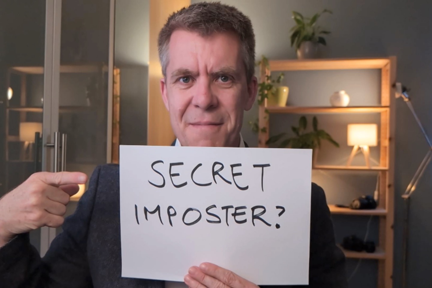 Benjamin Mitchell holding a sign saying - secret imposter?